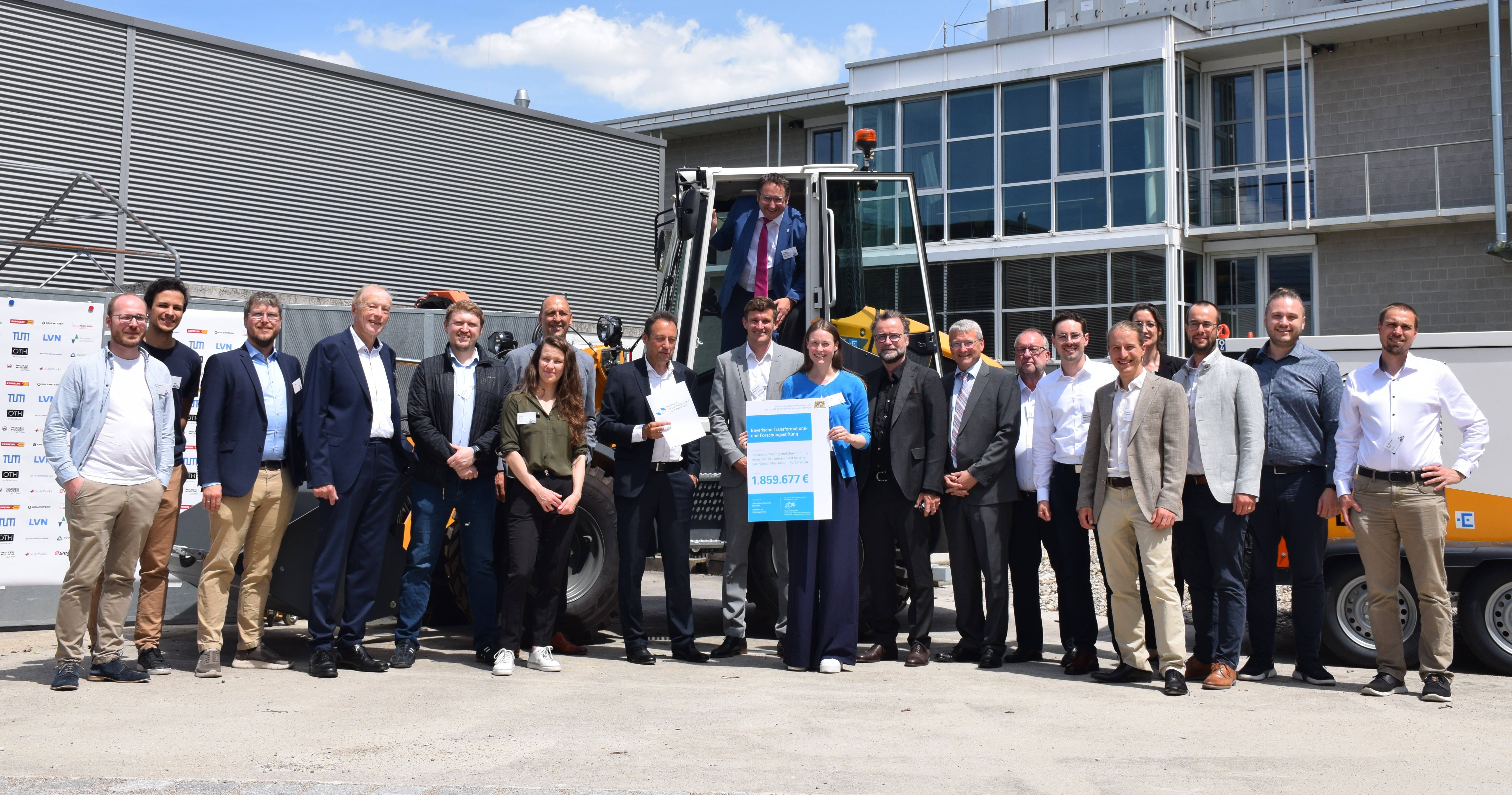 Staatssekretär Tobias Gotthardt auf einem E-Radlader mit Prof. Dr. Dr. h.c. (NAS RA) Arndt Bode (Präsident Bayerische Transformations- und Forschungsstiftung, 4. v. links), und Teilen des Forschungsverbundes, u.a. Prof. Markus Lienkamp (TUM), Prof. Matthias Wagensoner (Hochschule Landshut), Dr. Anne Fischer (TUM), Prof. Christoph Gehlen (TUM), Prof. Oliver Brückl (OTH Regensburg) (Quelle: Bayerische Transformations- und Forschungsstiftung).